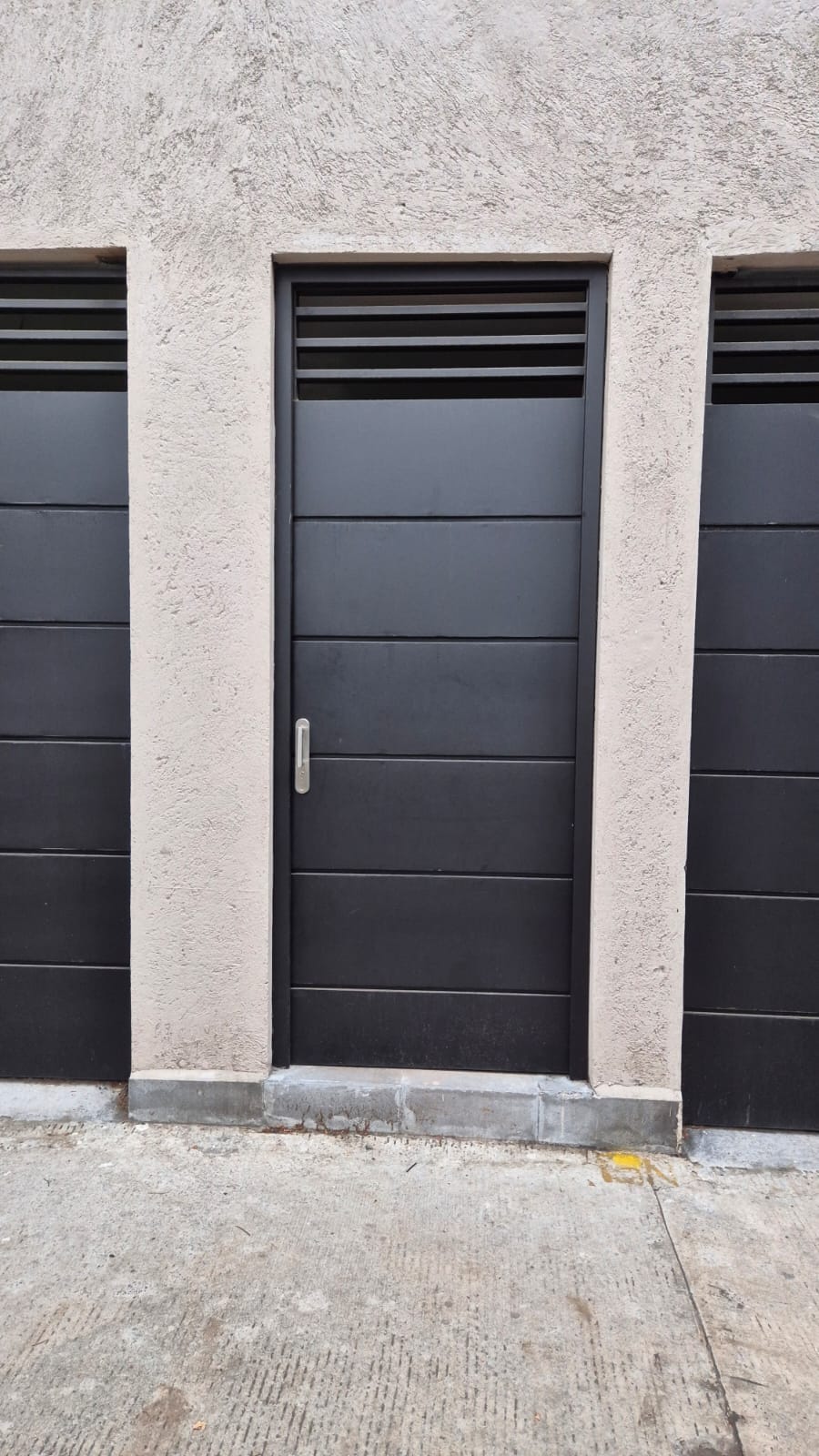 Puerta de herrería con ventilación en contexto residencial